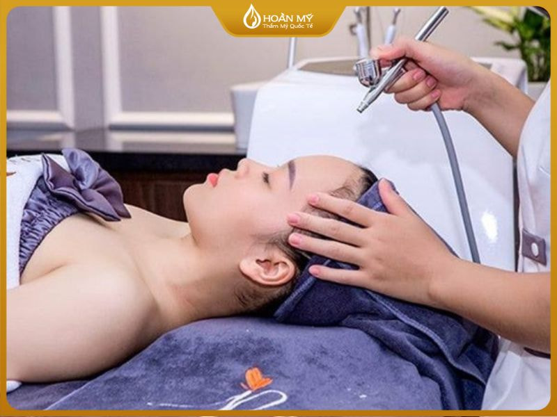 Kỹ thuật viên spa đang thực hiện bước đi oxy jet làm dịu và cấp ẩm cho da mặt